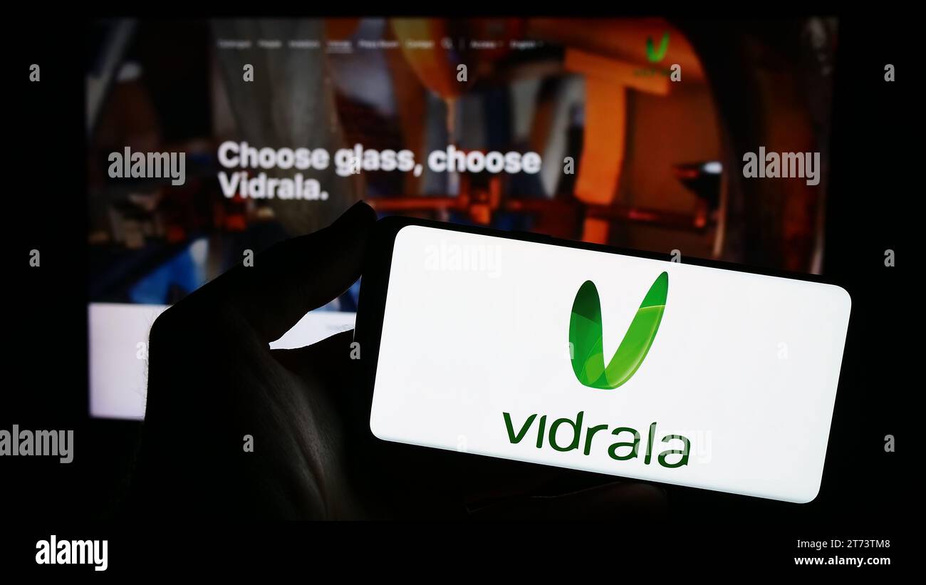 Persona che possiede uno smartphone con il logo della società spagnola di produzione del vetro Vidrala S.A. di fronte al sito Web. Concentrarsi sul display del telefono. Foto Stock