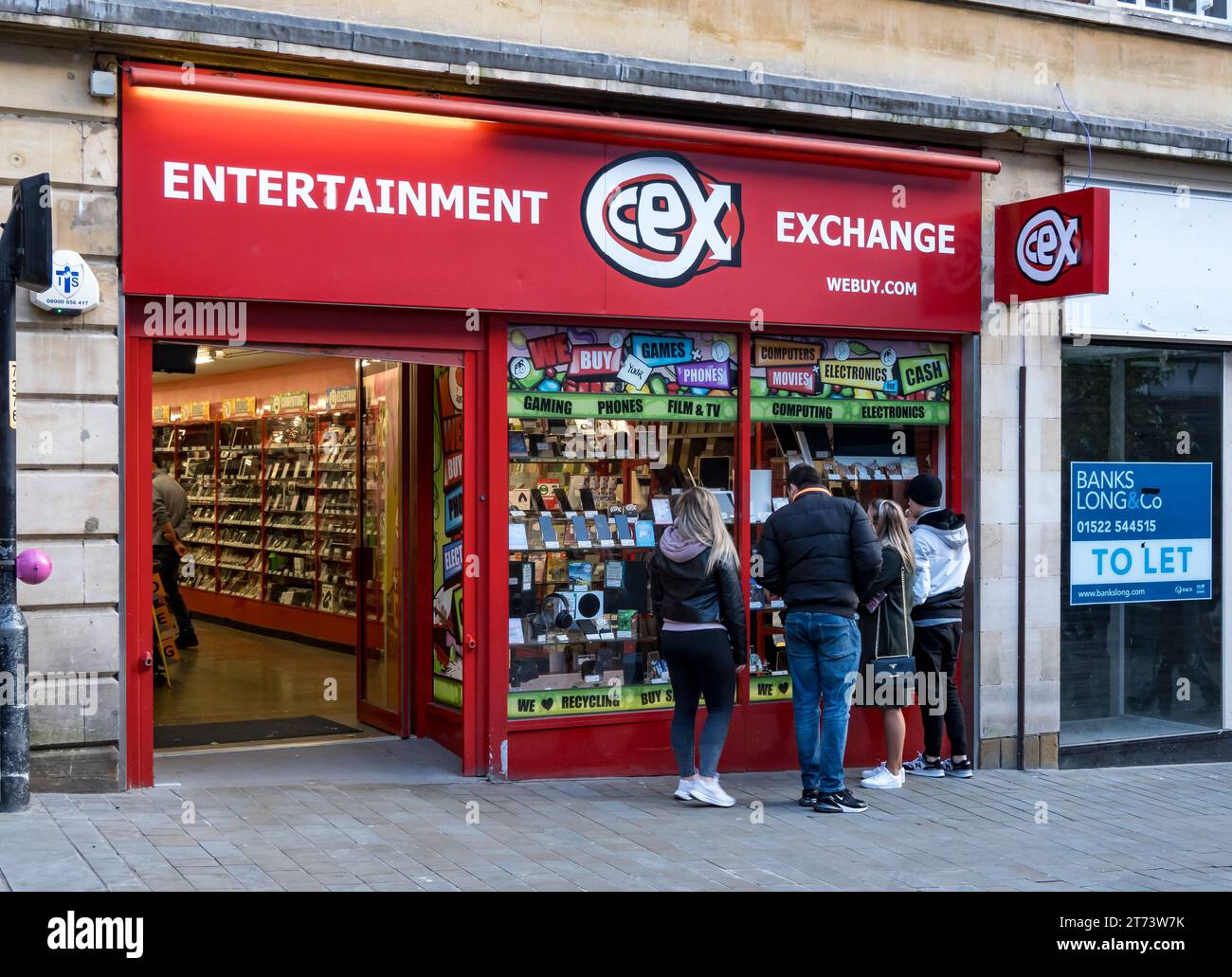 Persone che guardano nella vetrina del negozio CEX, High Street, Lincoln City, Lincolnshire, Inghilterra, REGNO UNITO Foto Stock