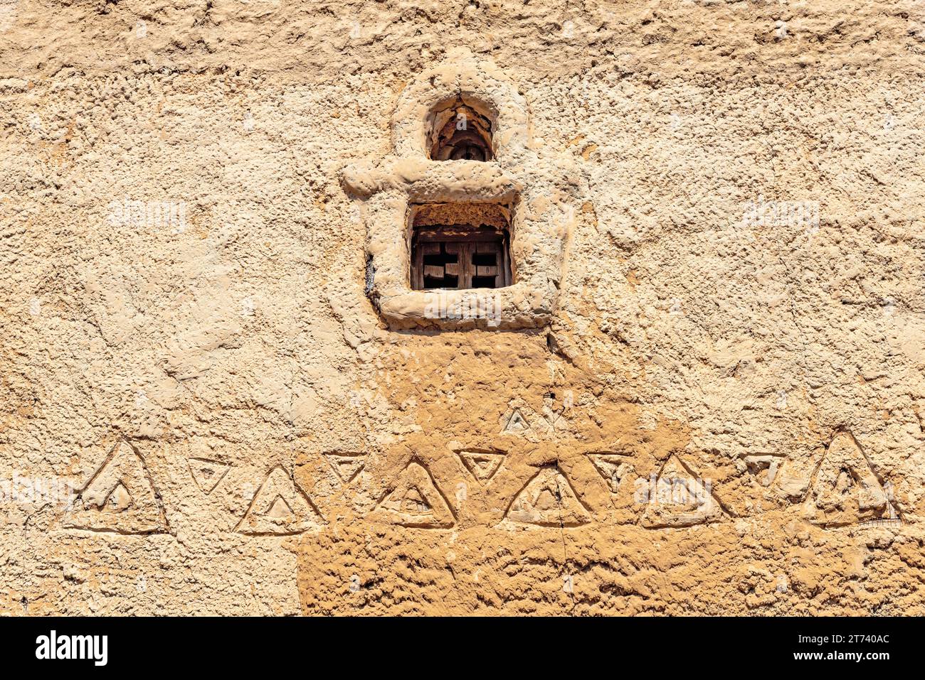 Parete in argilla con una piccola finestra e un ornamento nazionale musulmano Foto Stock