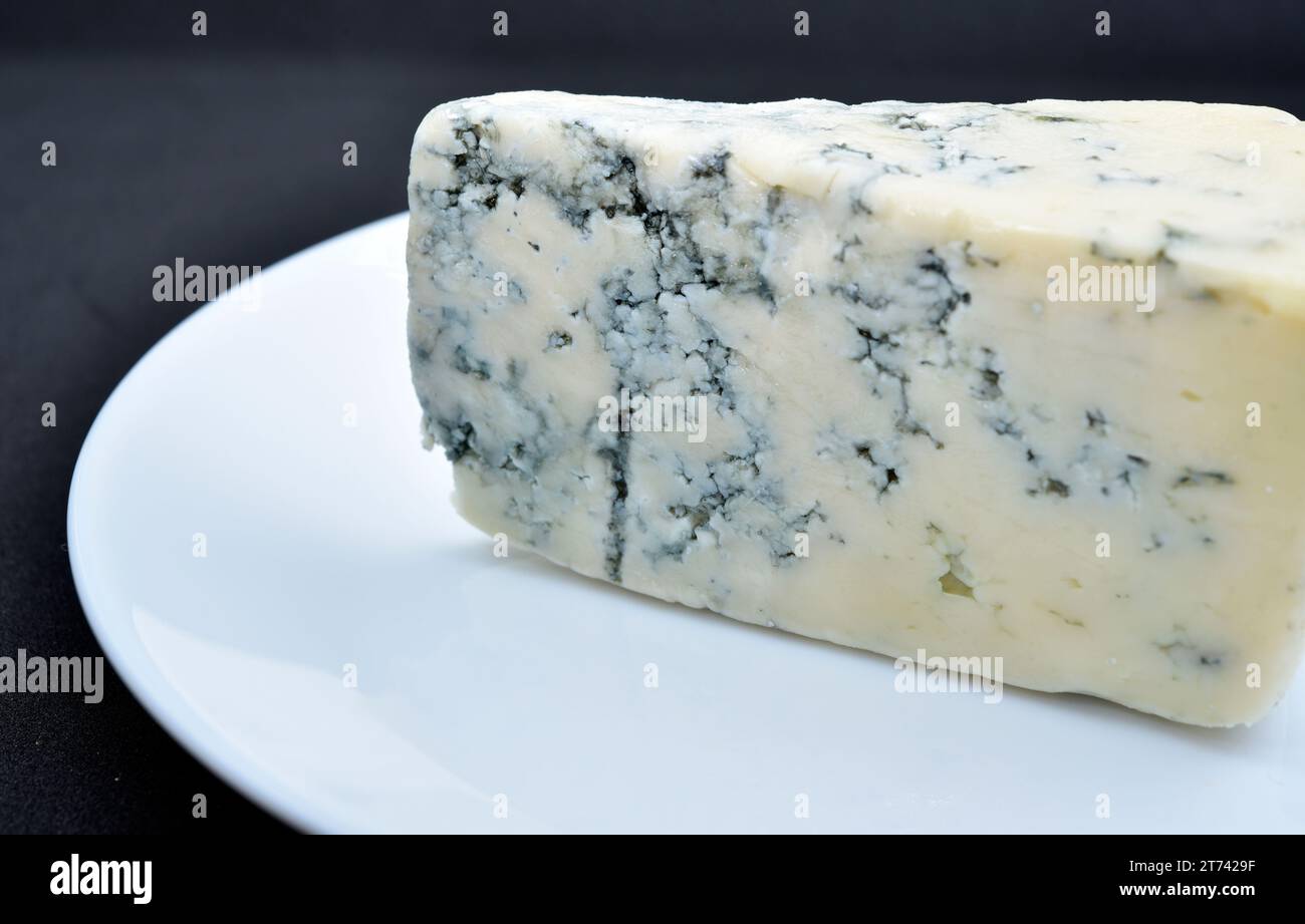 Un pezzo di formaggio con muffa blu su un piatto bianco. Formaggio delizioso. Foto Stock