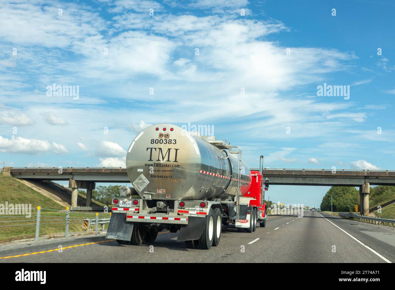 Lake Charles, USA - 23 ottobre 2023: Grande camion americano a cisterna rossa sull'autostrada sorpassato da un'auto prvate, Foto Stock