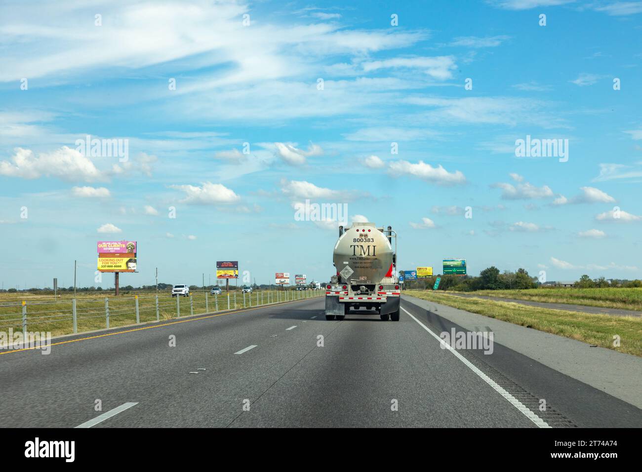 Lake Charles, USA - 23 ottobre 2023: Grande camion americano a cisterna rossa sull'autostrada sorpassato da un'auto prvate, Foto Stock