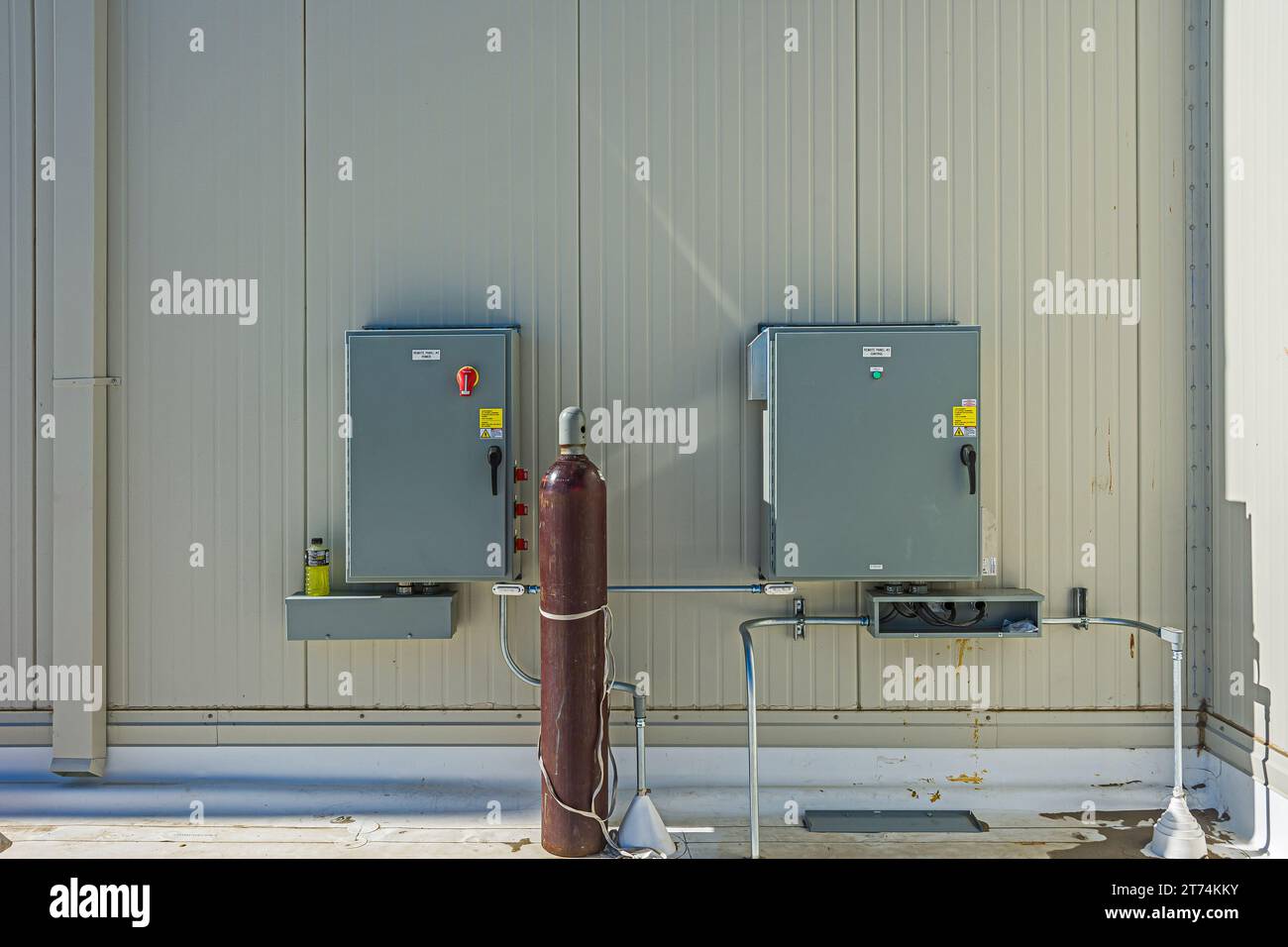 Pannelli di controllo elettrici sulla parete esterna sul tetto del magazzino di stoccaggio a freddo (refrigerazione industriale) durante la costruzione con bombola di gas marrone. Foto Stock