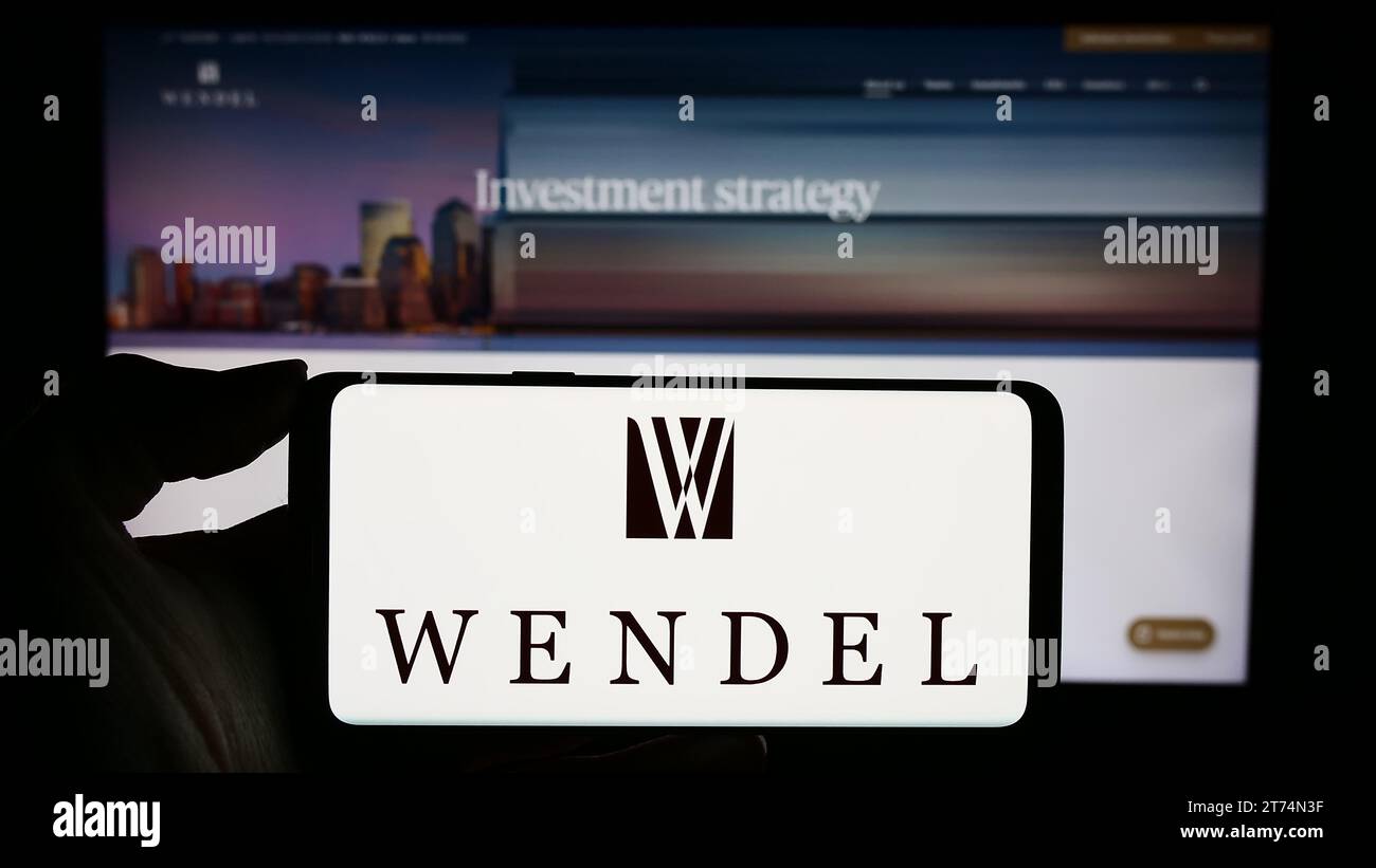 Persona che possiede uno smartphone con il logo della società di investimento francese Wendel se davanti al sito Web. Concentrarsi sul display del telefono. Foto Stock
