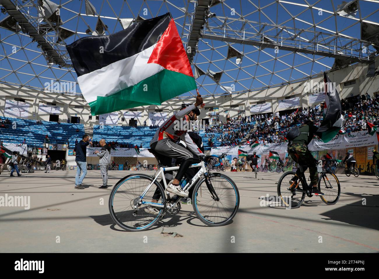 Gli yemeniti tengono in mano bandiere palestinesi, ballano e cavalcano una bicicletta durante una veglia per mostrare solidarietà al popolo palestinese, a Sana'a, Yemen, il 13 novembre 2023. Migliaia di israeliani e palestinesi sono morti da quando il gruppo militante Hamas ha lanciato un attacco senza precedenti contro Israele dalla Striscia di Gaza il 7 ottobre e gli scioperi israeliani sull'enclave palestinese. Foto Stock