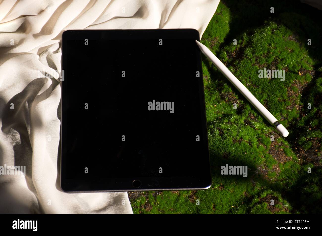 Un moderno tablet computer appoggiato su una superficie in tessuto accanto a un oggetto decorativo Foto Stock