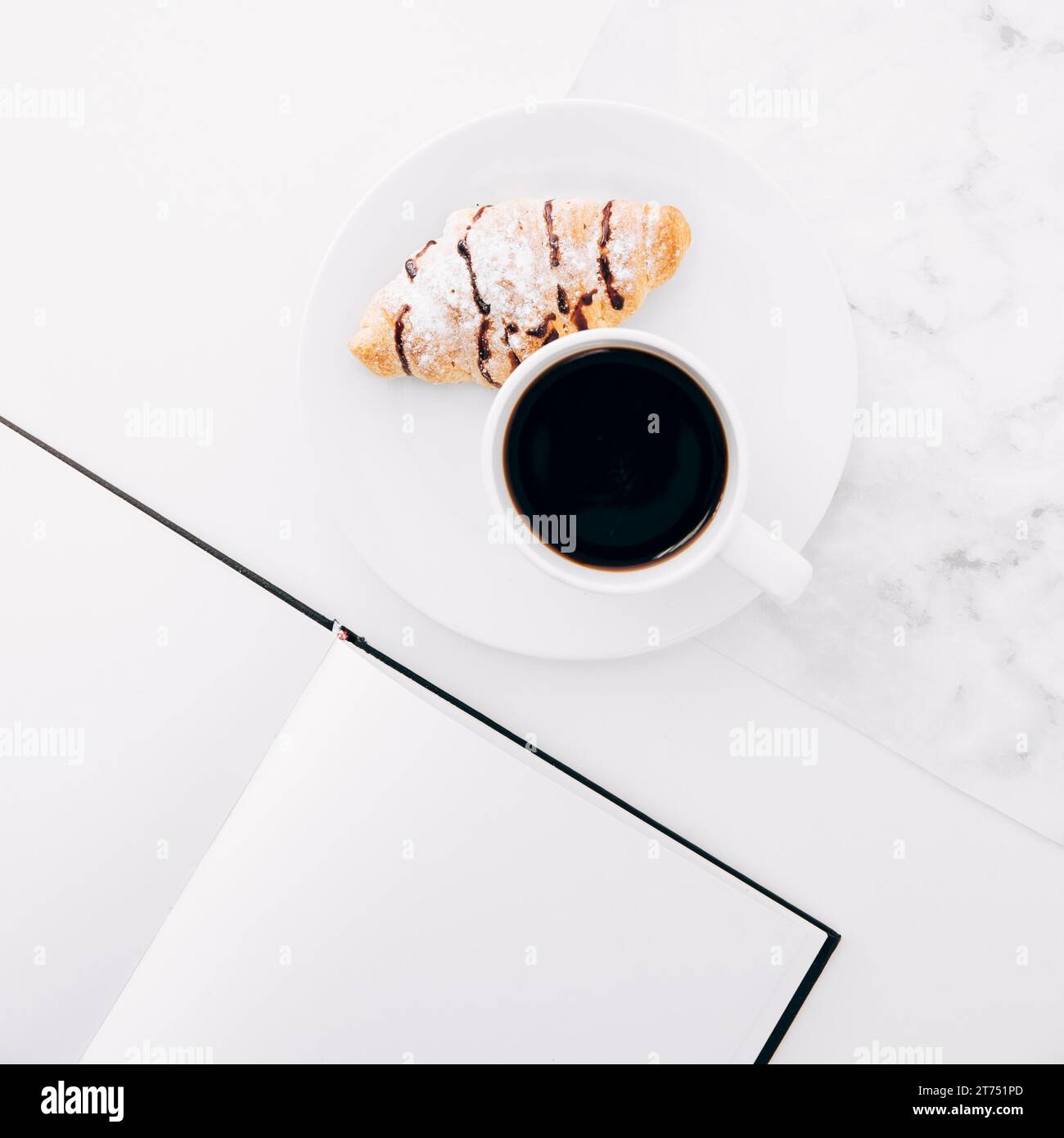 Vassoio per caffè croissant vicino al quaderno di pagina vuota Foto Stock