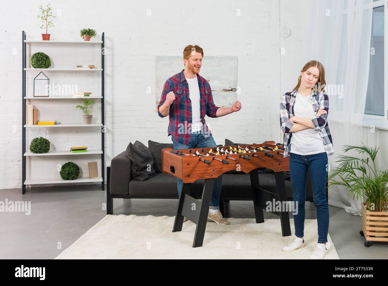 Uomo che stringe il pugno di gioia, donna triste, salotto moderno Foto Stock