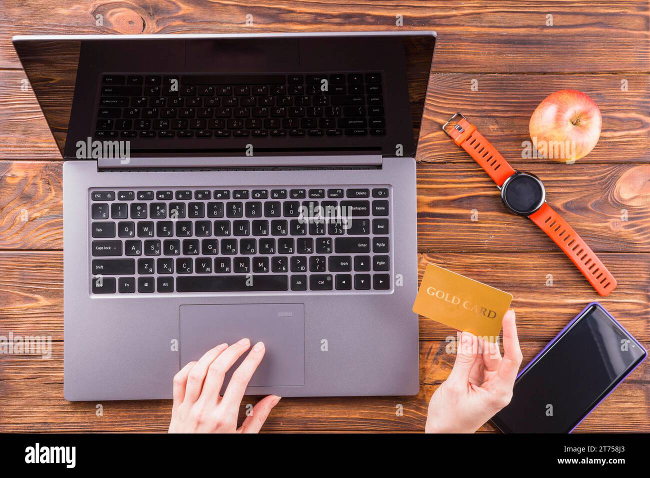 Persona che usa la carta d'oro per fare acquisti online con un tavolo di legno per computer portatile Foto Stock