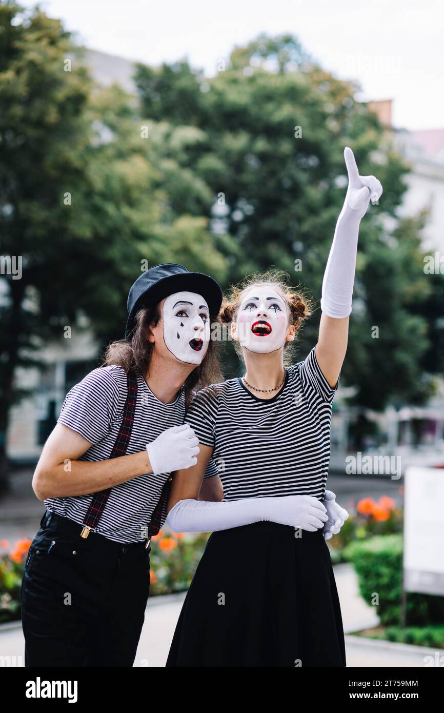 Mimo femminile rivolto verso l'alto che mostra qualcosa di mimo maschile Foto Stock