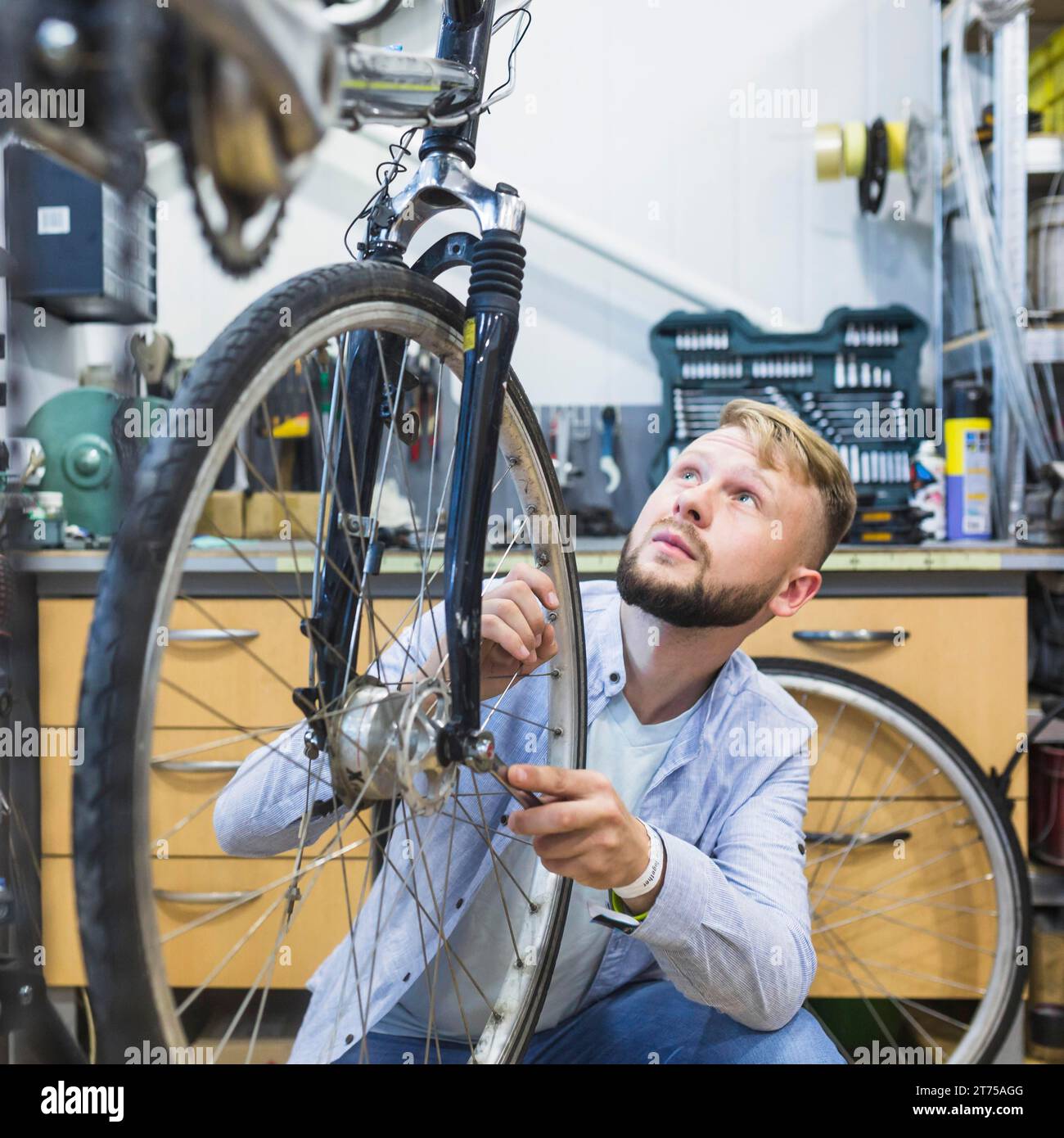 Meccanico di biciclette maschio che ripara il negozio di pneumatici per biciclette Foto Stock