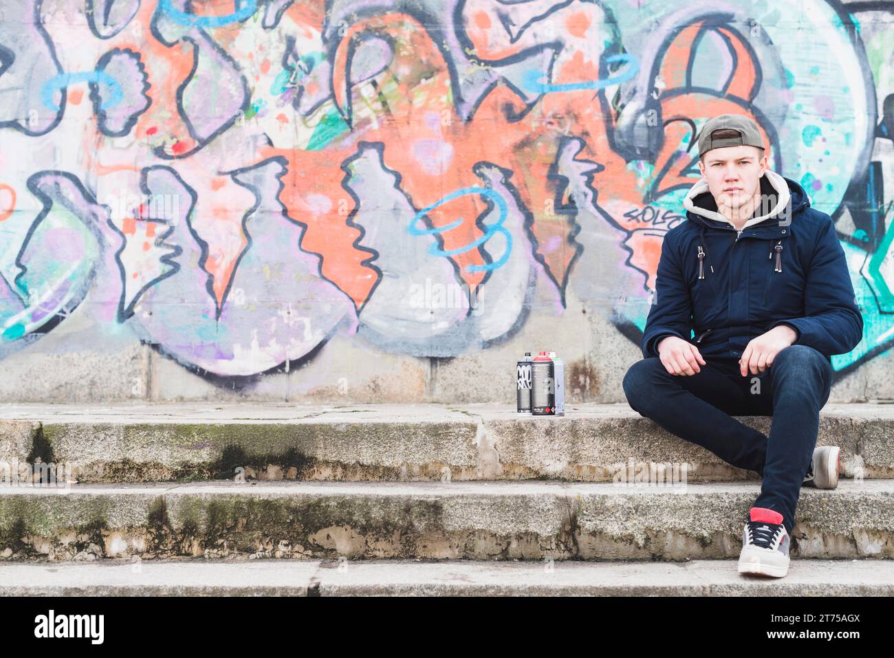 Uomo seduto davanti al muro dei graffiti Foto Stock