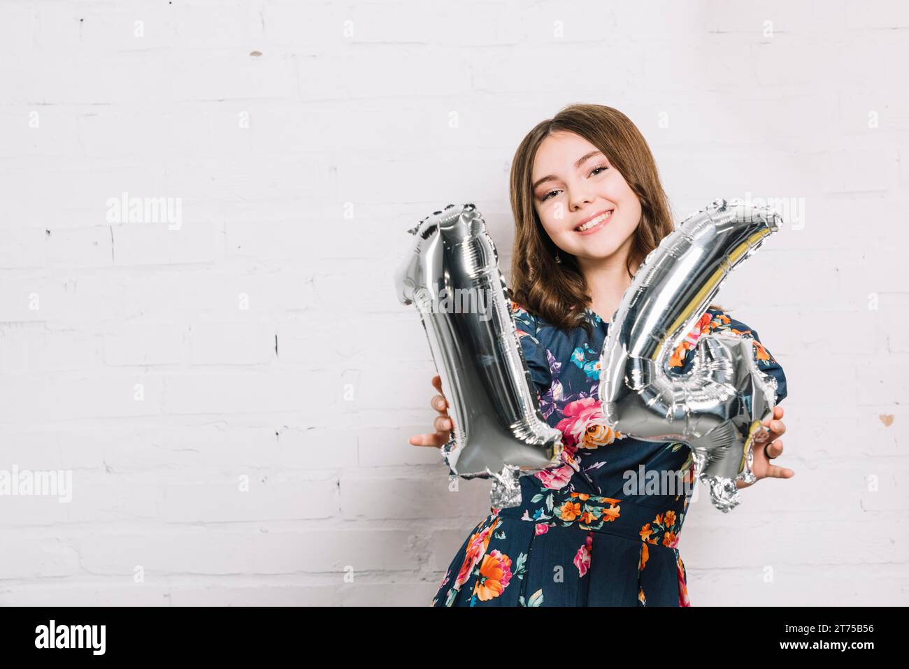 Ritrattista sorridente che mostra un palloncino in alluminio con numero 14 Foto Stock
