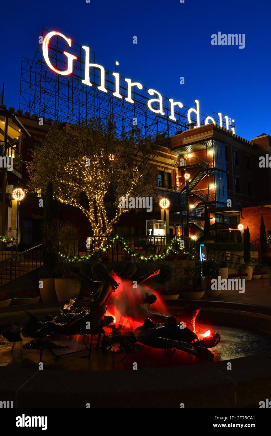 L'insegna su Ghirardelli Square a San Francisco è illuminata al tramonto, così come la fontana nella piazza Foto Stock