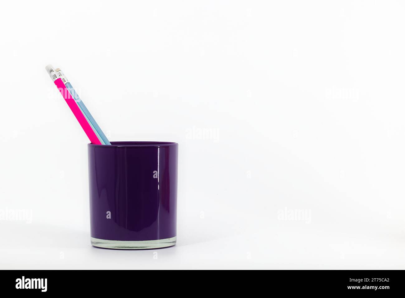 Un organizer da tavolo in vetro viola su sfondo bianco contiene tre matite con cancelletti di colore rosa, blu e navy. Foto Stock Un organizer da tavolo in vetro viola su sfondo bianco contiene tre matite con cancelletti di colore rosa, blu e navy. Foto Stock