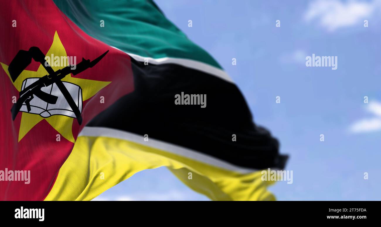 La bandiera del Mozambico sventola con orgoglio, con il suo emblema unico contro un cielo parzialmente nuvoloso, a simboleggiare la libertà e la speranza Foto Stock