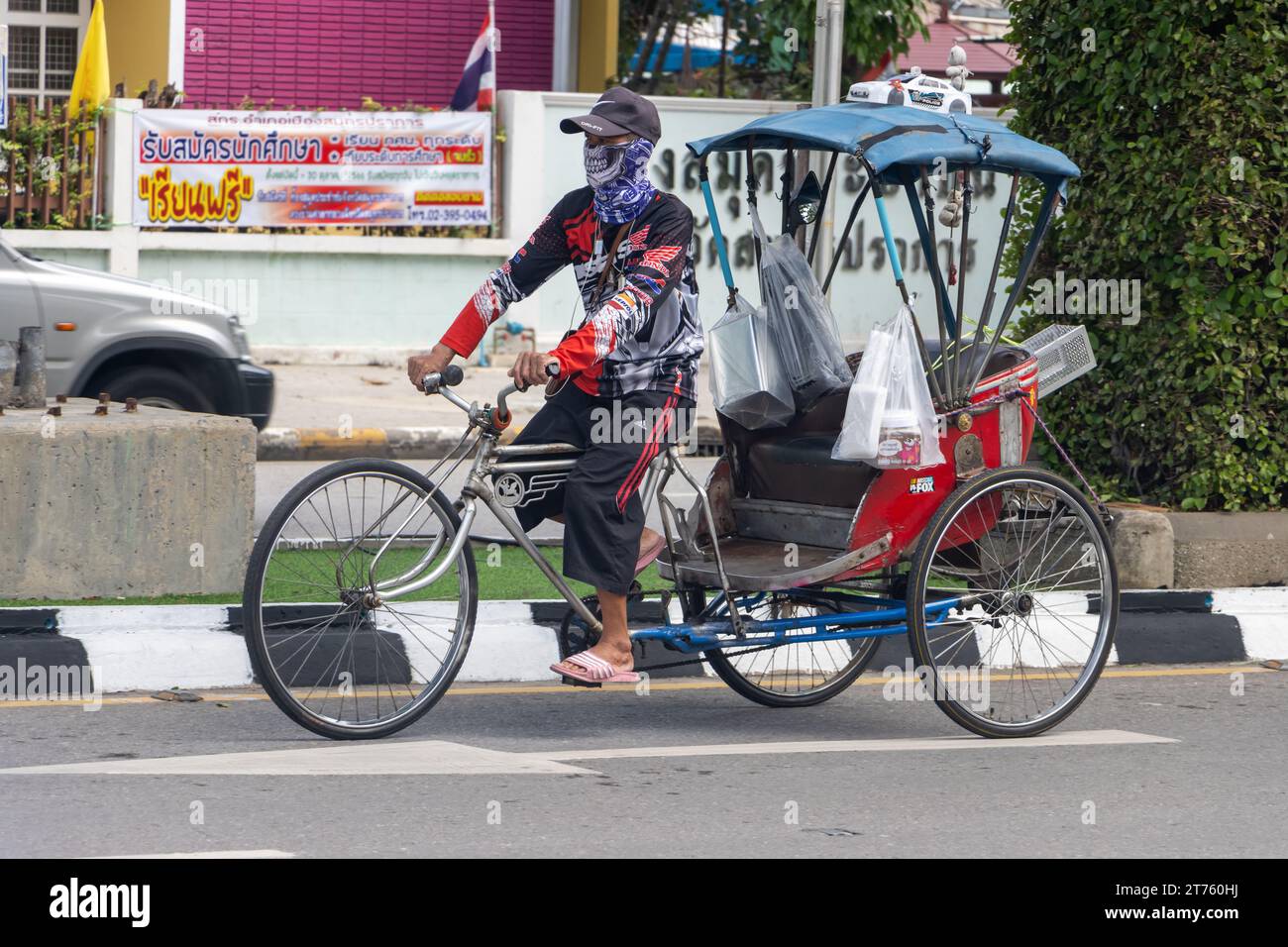 SAMUT PRAKAN, THAILANDIA, 11 ottobre 2023, Un uomo guida un triciclo per trasportare un passeggero nel traffico cittadino Foto Stock