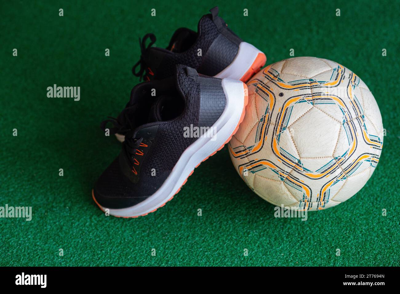 In attesa che il piede di tela tocchi il calcio nero e una palla bianca su erba sintetica verde. Foto Stock