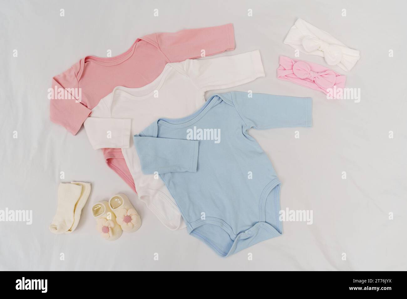 set di vestiti e accessori per bambini su un letto bianco Foto Stock