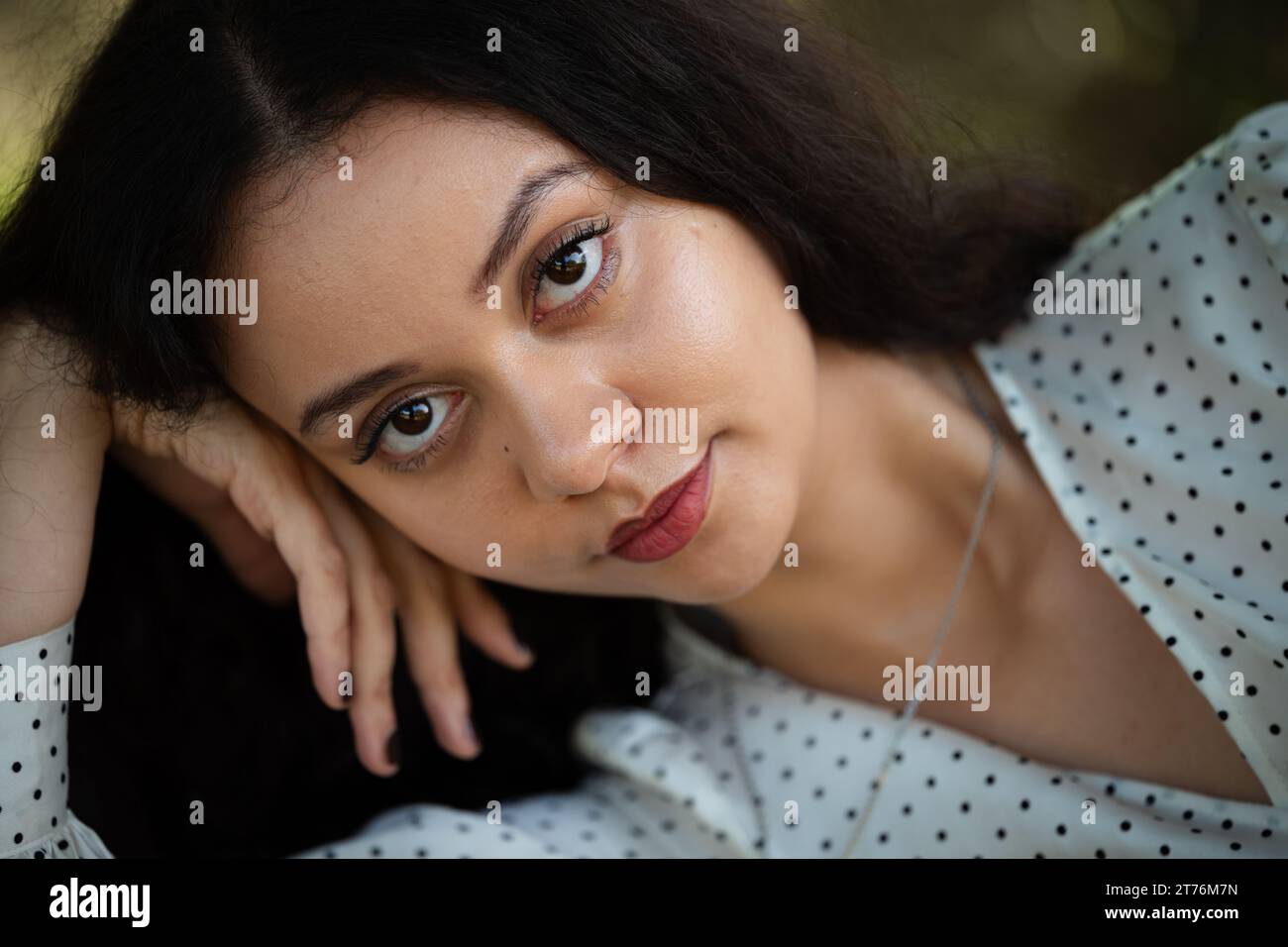 Una giovane donna con un vestito bianco che guarda nella telecamera Foto Stock