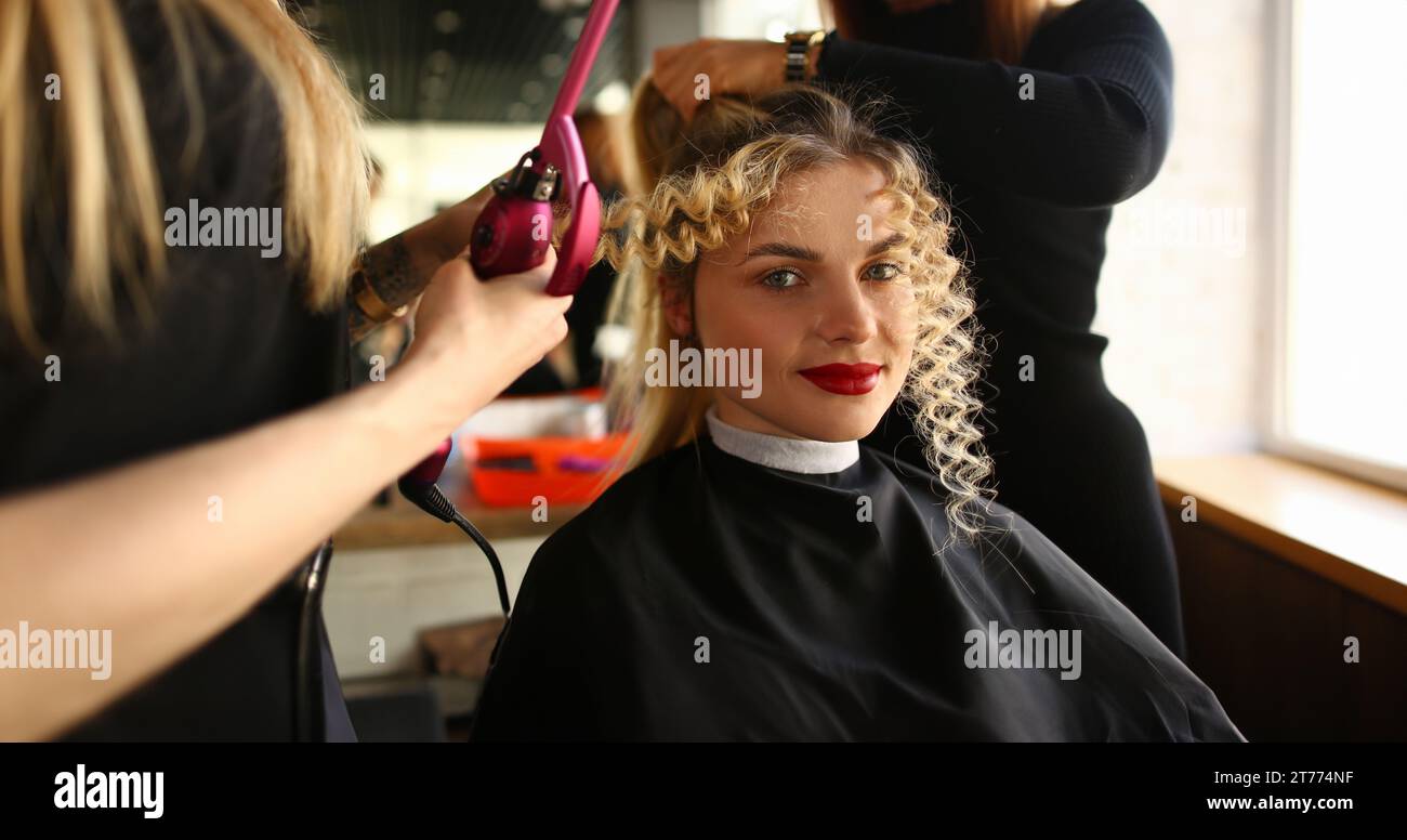 Giovane donna di ottenere capelli ricci da ferro arricciacapelli Foto Stock