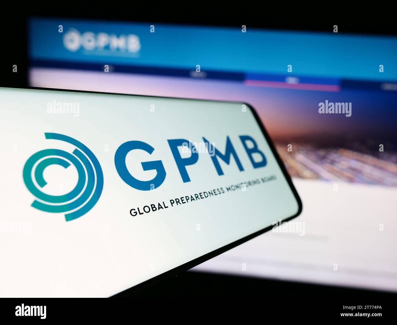 Smartphone con logo della scheda di monitoraggio della preparazione globale (GPMB) davanti al sito Web. Mettere a fuoco il display centrale sinistro del telefono. Foto Stock