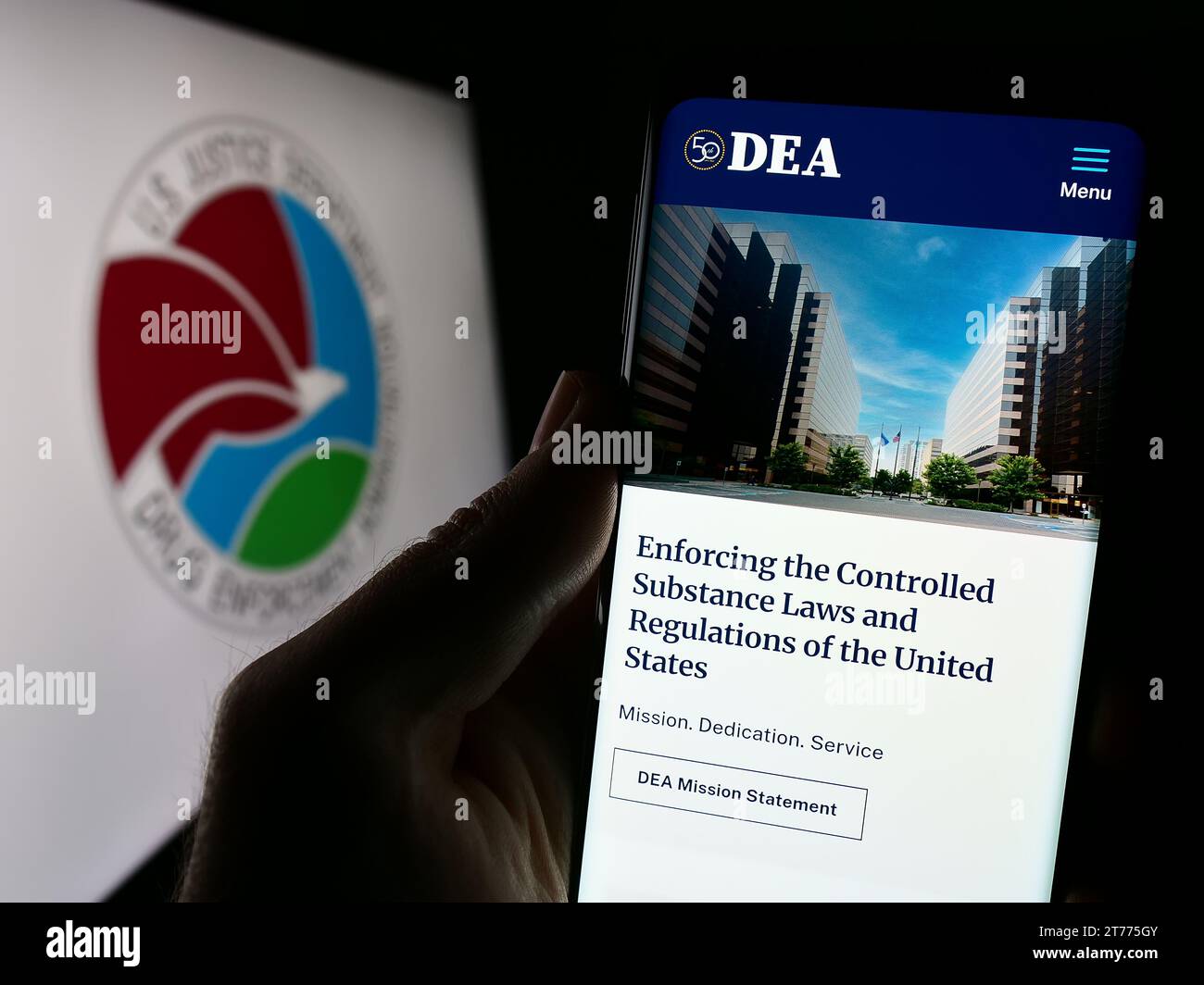 Persona che possiede un telefono cellulare con un sito web della United States Drug Enforcement Administration (DEA) con sigillo. Concentrarsi sul centro del display del telefono. Foto Stock