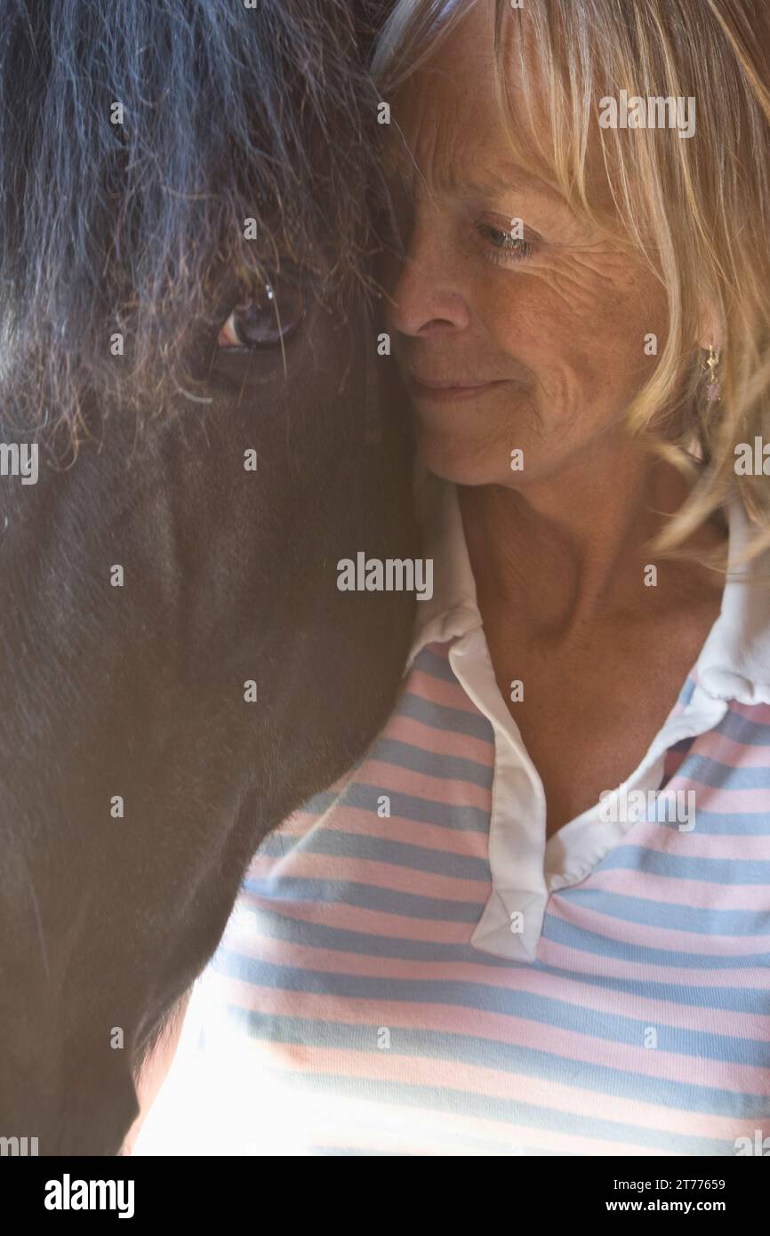 In prossimità di una donna matura in piedi accanto alla testa di cavallo Foto Stock