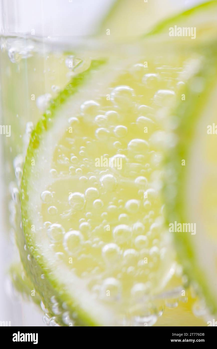 Extreme close up di fettine di lime galleggianti in acqua frizzante Foto Stock