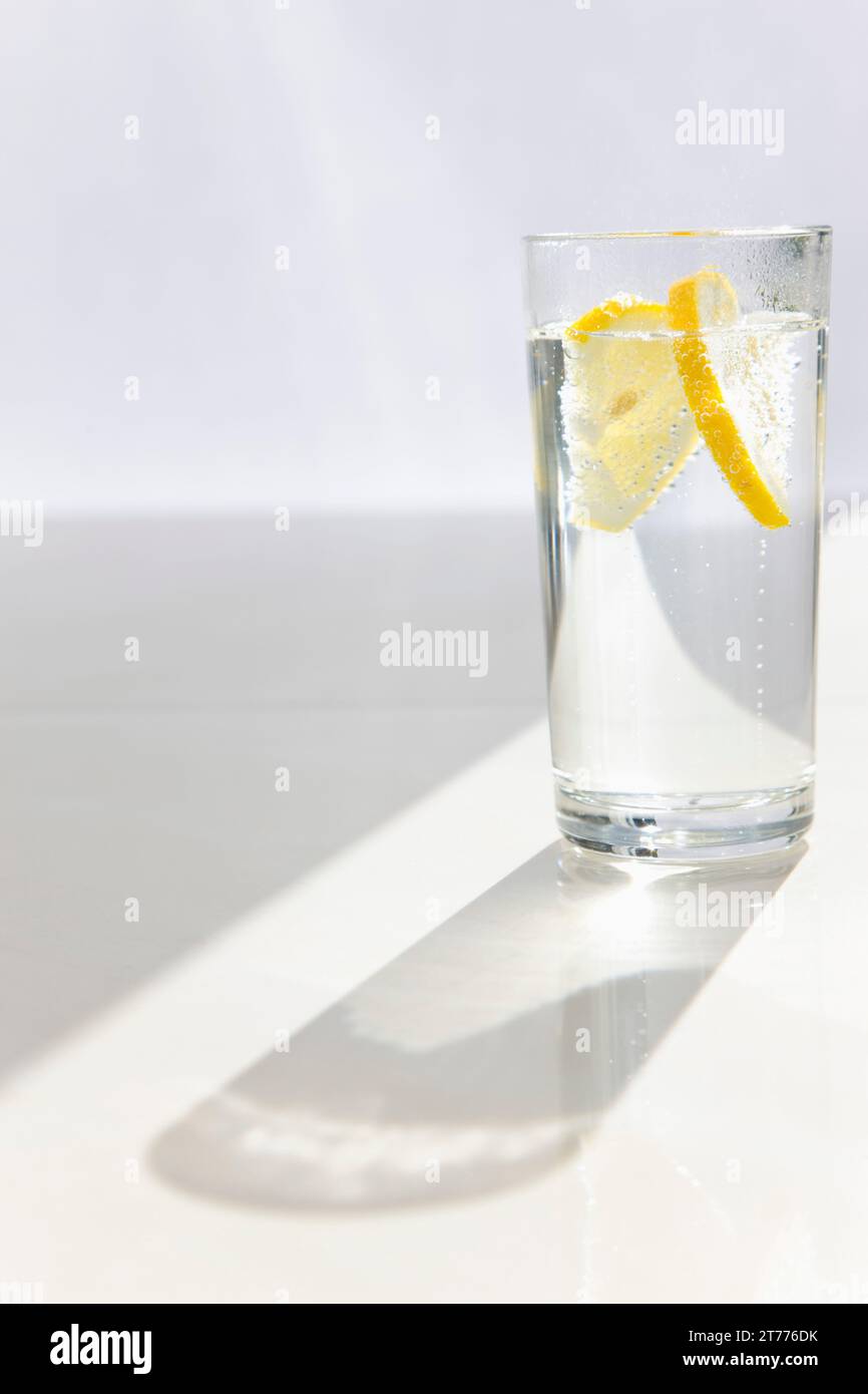 Bicchiere di acqua frizzante con spicchi di limone Foto Stock