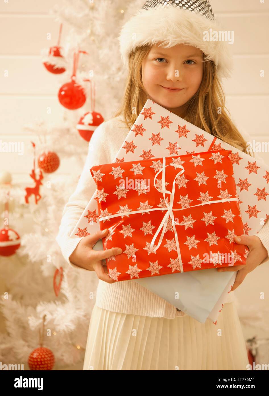 Ragazza in piedi vicino a un albero di Natale che regge regali Foto Stock