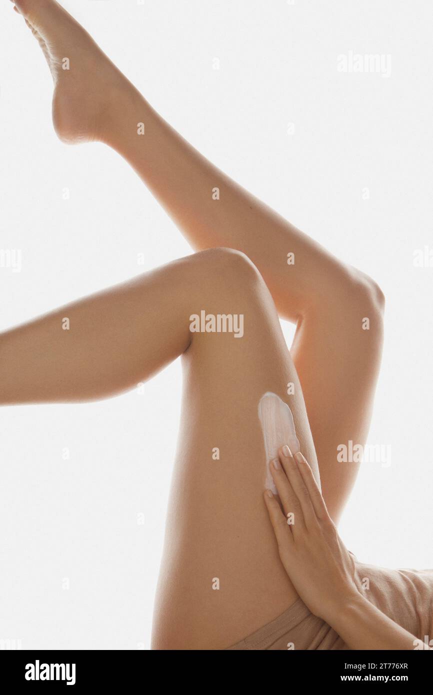 Donna di applicare la lozione per il corpo sulle gambe Foto Stock
