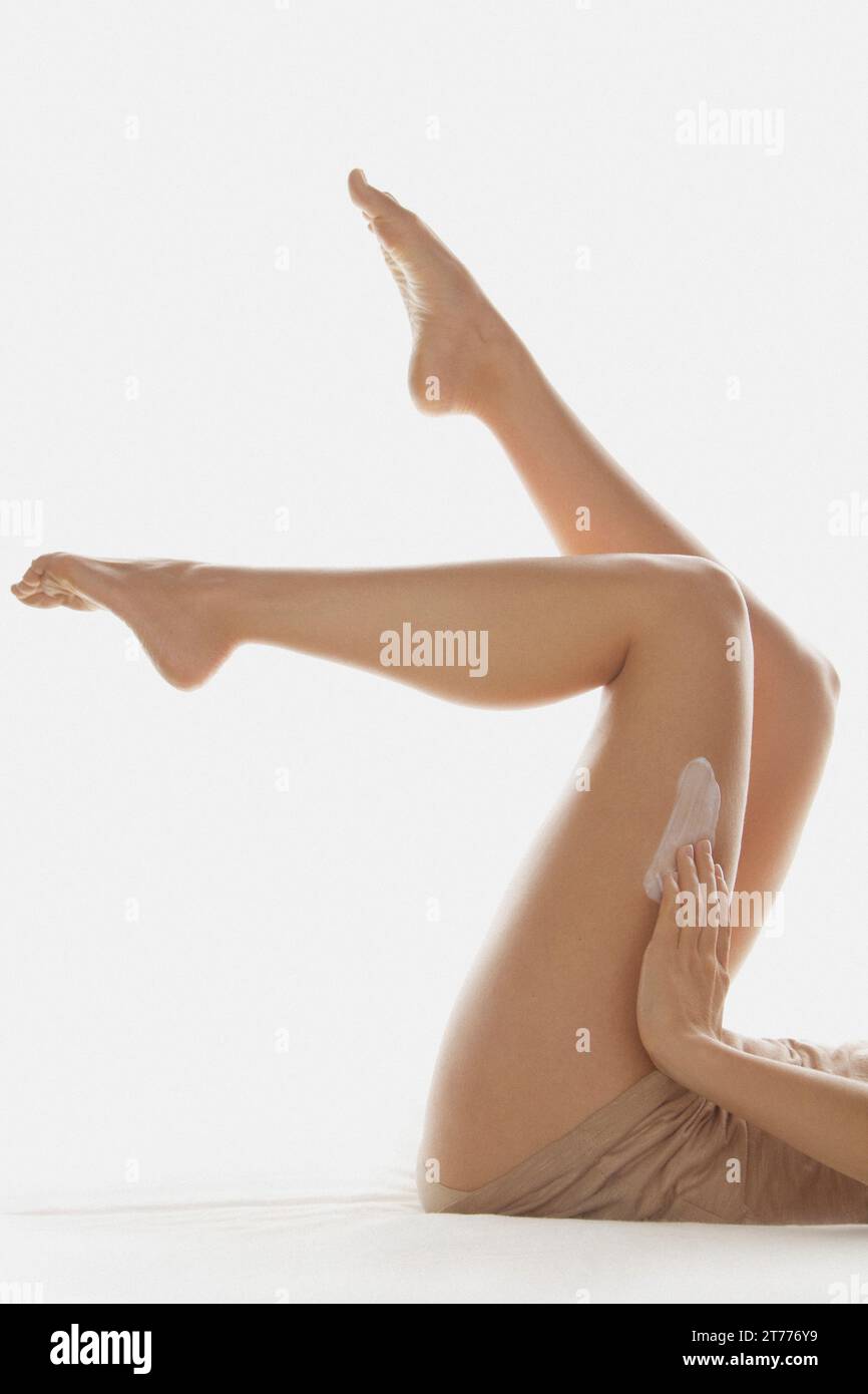Donna di applicare la lozione per il corpo sulle gambe Foto Stock