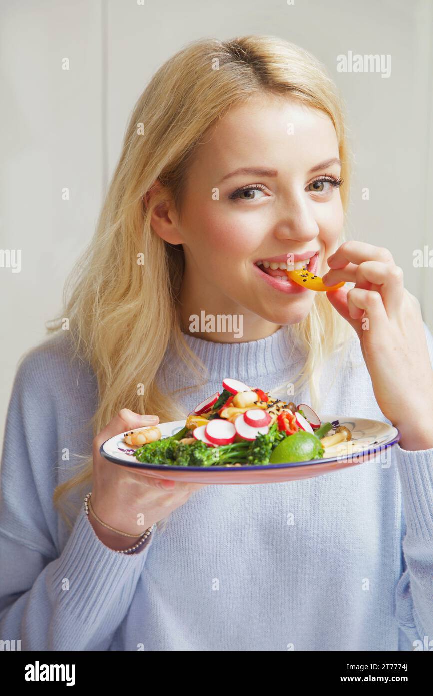 Donna di mangiare rosolare le verdure Foto Stock