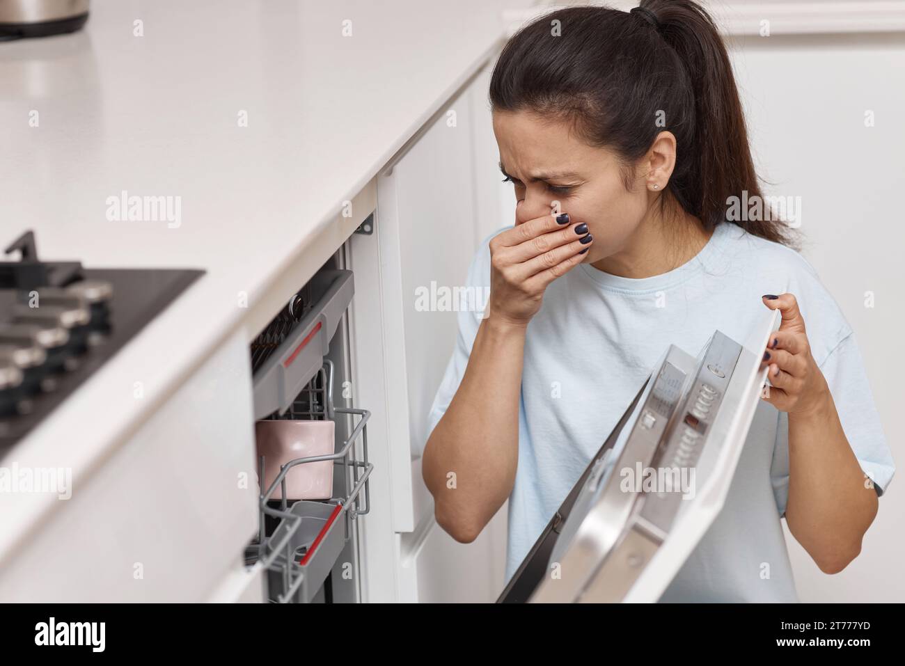la donna ha un odore strano e terribile proveniente dalla lavastoviglie in cucina Foto Stock