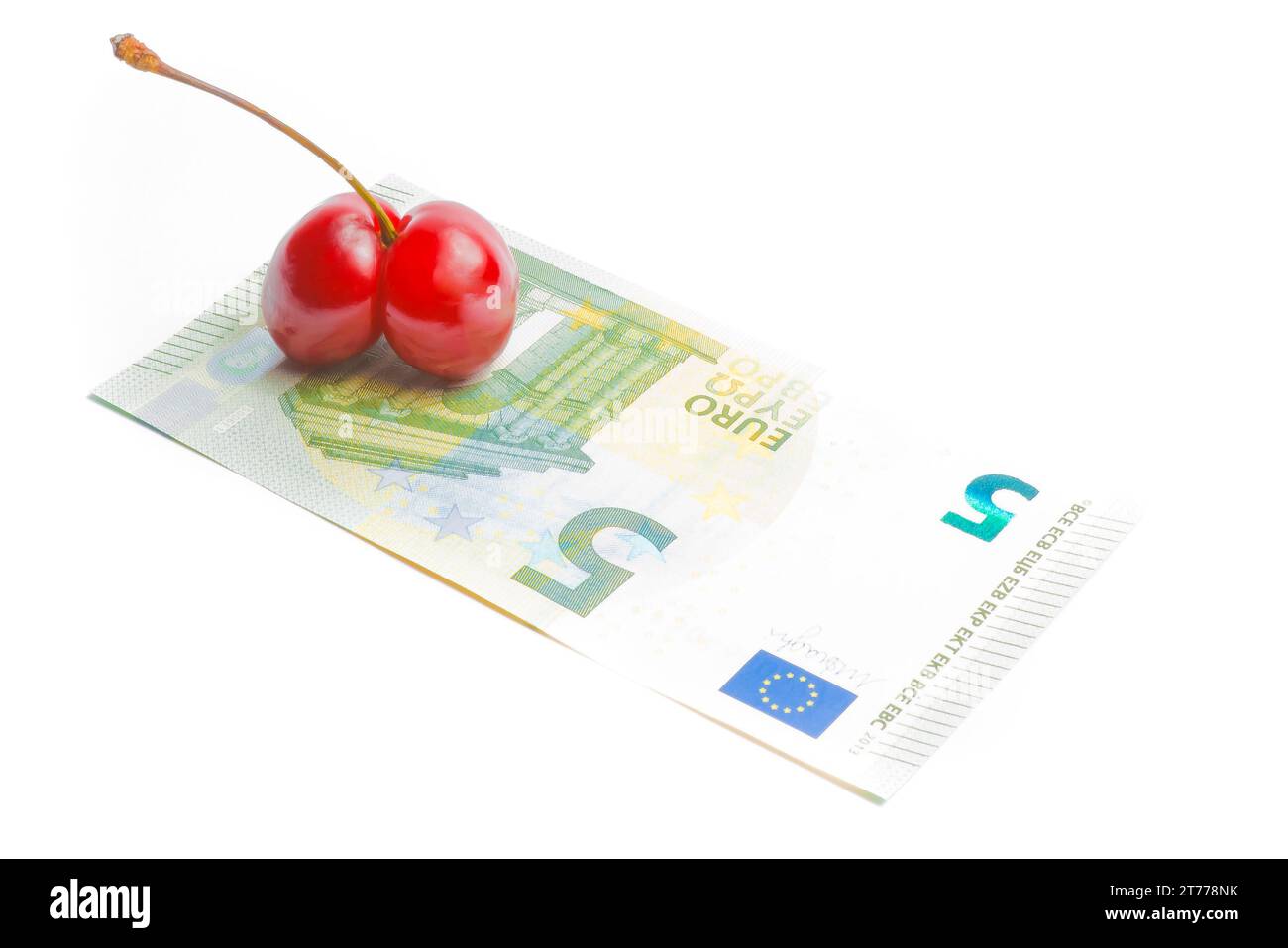 ciliegie gemelle vicino alla banconota in euro su sfondo bianco Foto Stock