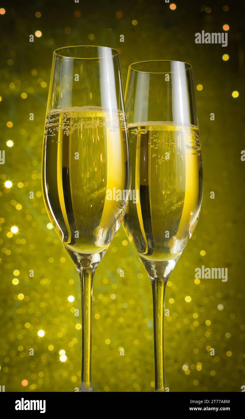 due flute di champagne con bollicine dorate su sfondo bokeh giallo chiaro Foto Stock