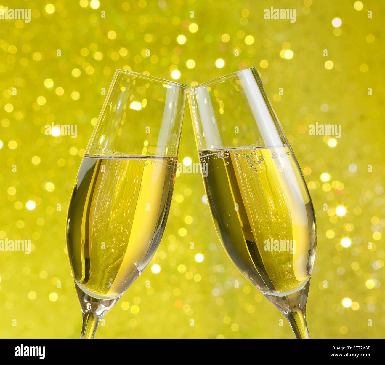 due flute di champagne con bolle d'oro fanno il tifo su sfondo giallo chiaro bokeh Foto Stock