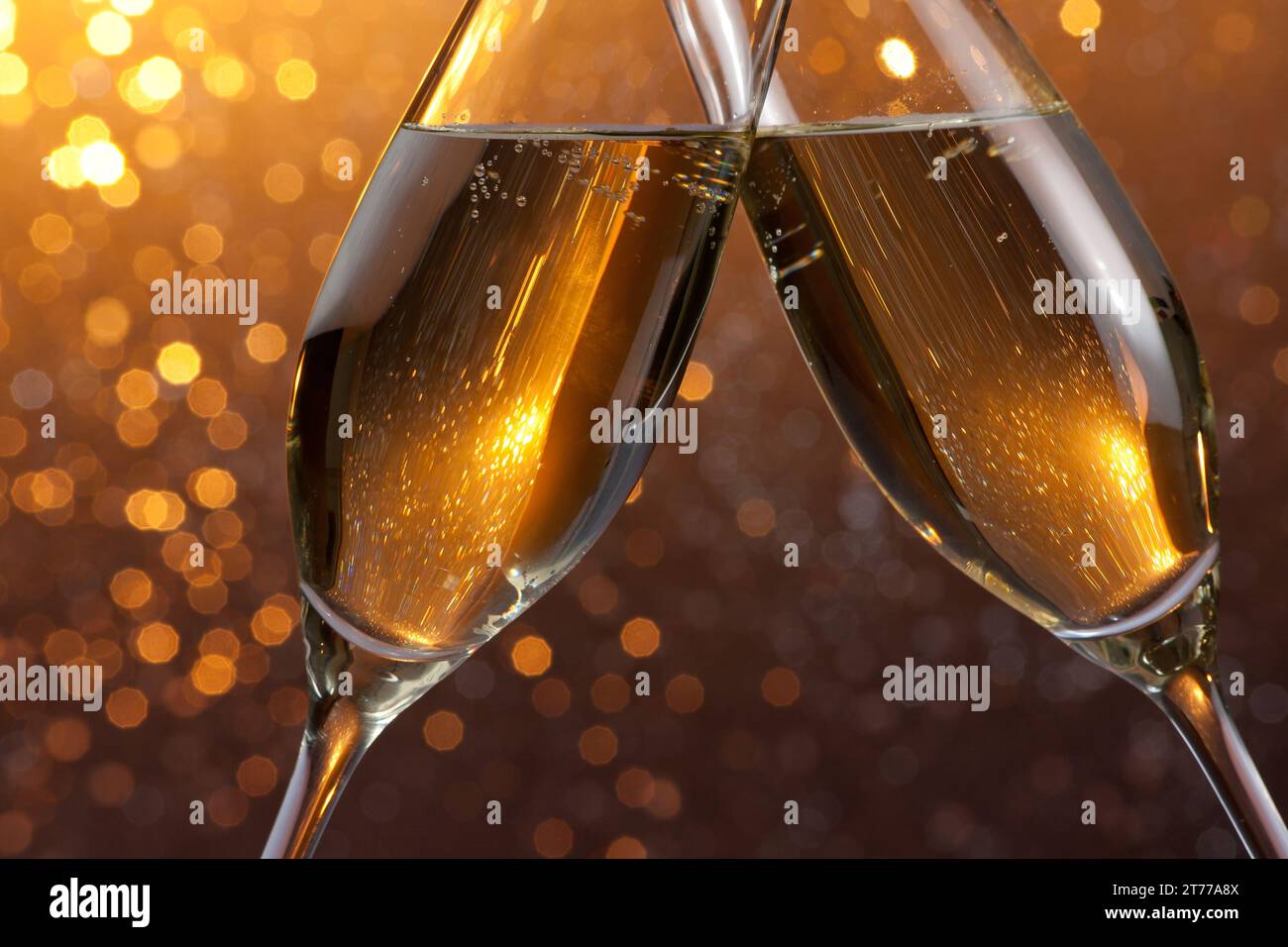 dettaglio di un flute di champagne con bollicine dorate per esultare su sfondo bokeh chiaro arancione Foto Stock