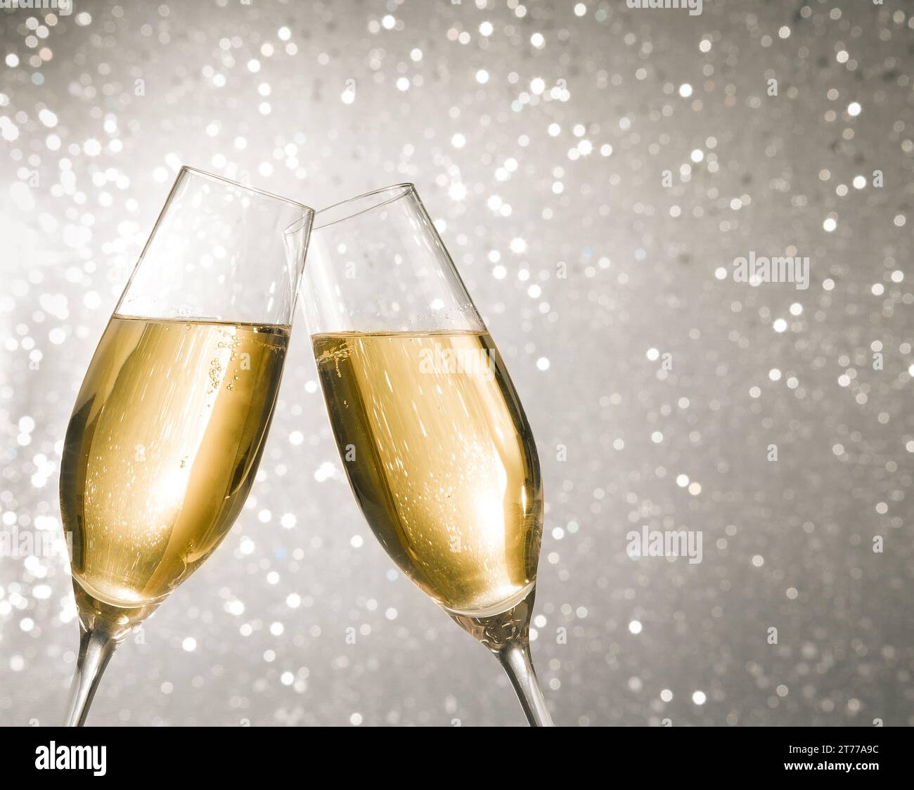 flauti di champagne con bolle d'oro fanno il tifo su sfondo bokeh chiaro argentato con spazio per il testo Foto Stock