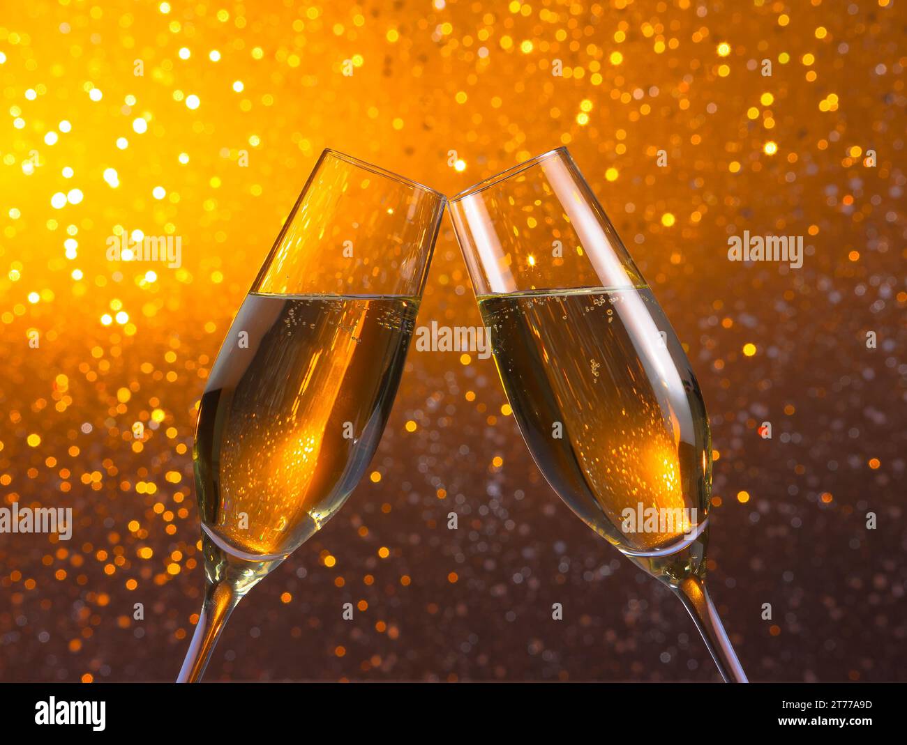 un paio di flauti di champagne fa il tifo su uno sfondo bokeh chiaro e dorato Foto Stock