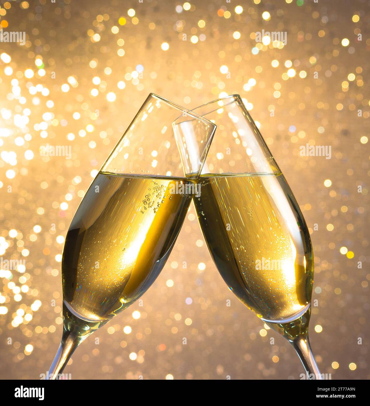 flauti di champagne con bolle d'oro fanno il tifo su sfondo bokeh chiaro Foto Stock