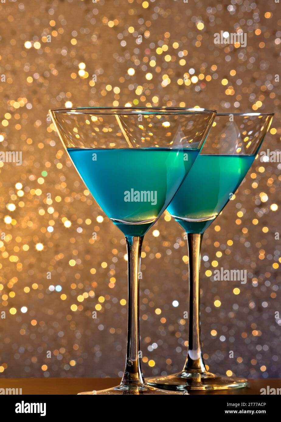 un paio di bicchieri di cocktail blu su sfondo bokeh chiaro e dorato sul tavolo da bar Foto Stock