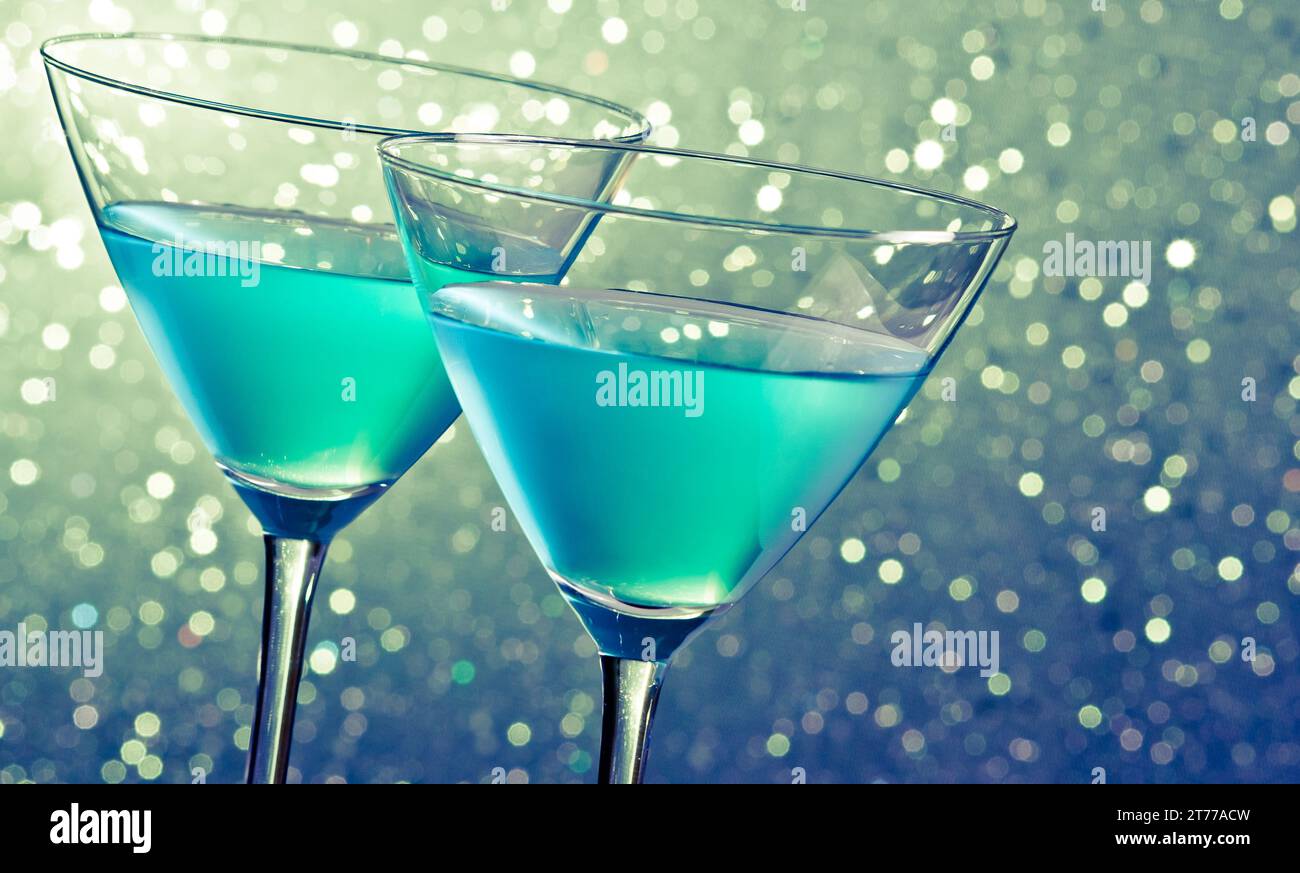 due bicchieri di cocktail blu su sfondo bokeh chiaro e verde scuro sul tavolo Foto Stock