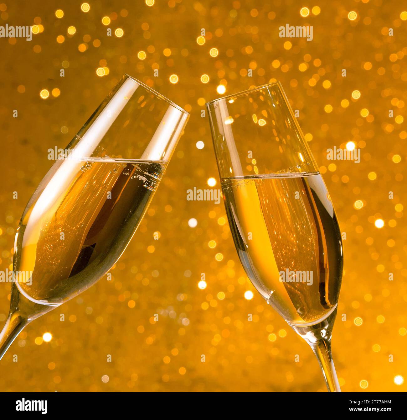 due flute di champagne con bolle d'oro fanno il tifo su sfondo bokeh chiaro dorato Foto Stock