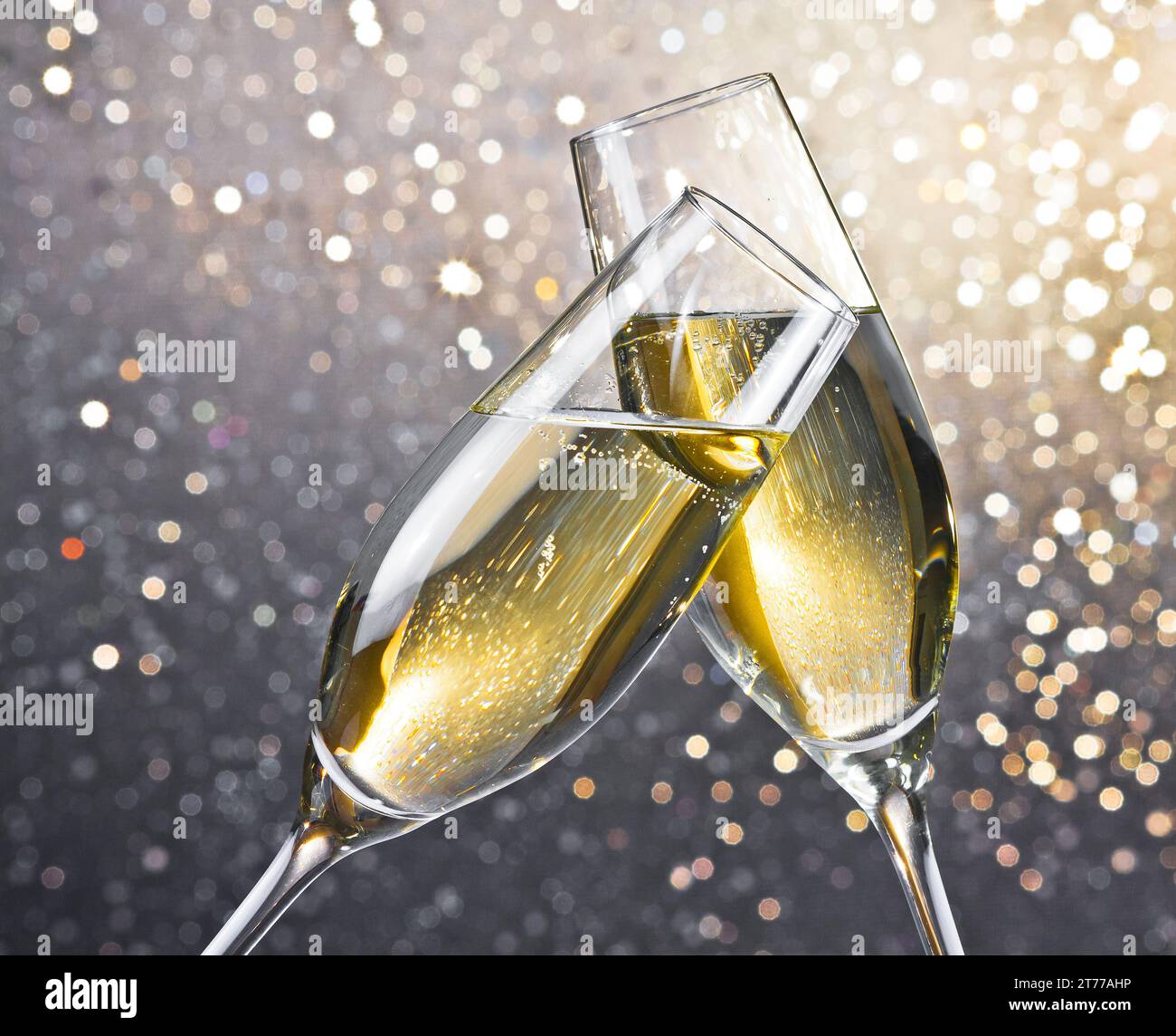 i flauti di champagne con bolle d'oro fanno il tifo su sfondo bokeh chiaro con spazio per il testo Foto Stock