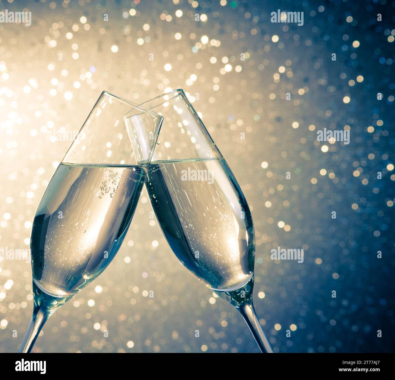 flauti di champagne con bolle d'oro fanno il tifo su sfondo bokeh chiaro blu con spazio per il testo Foto Stock