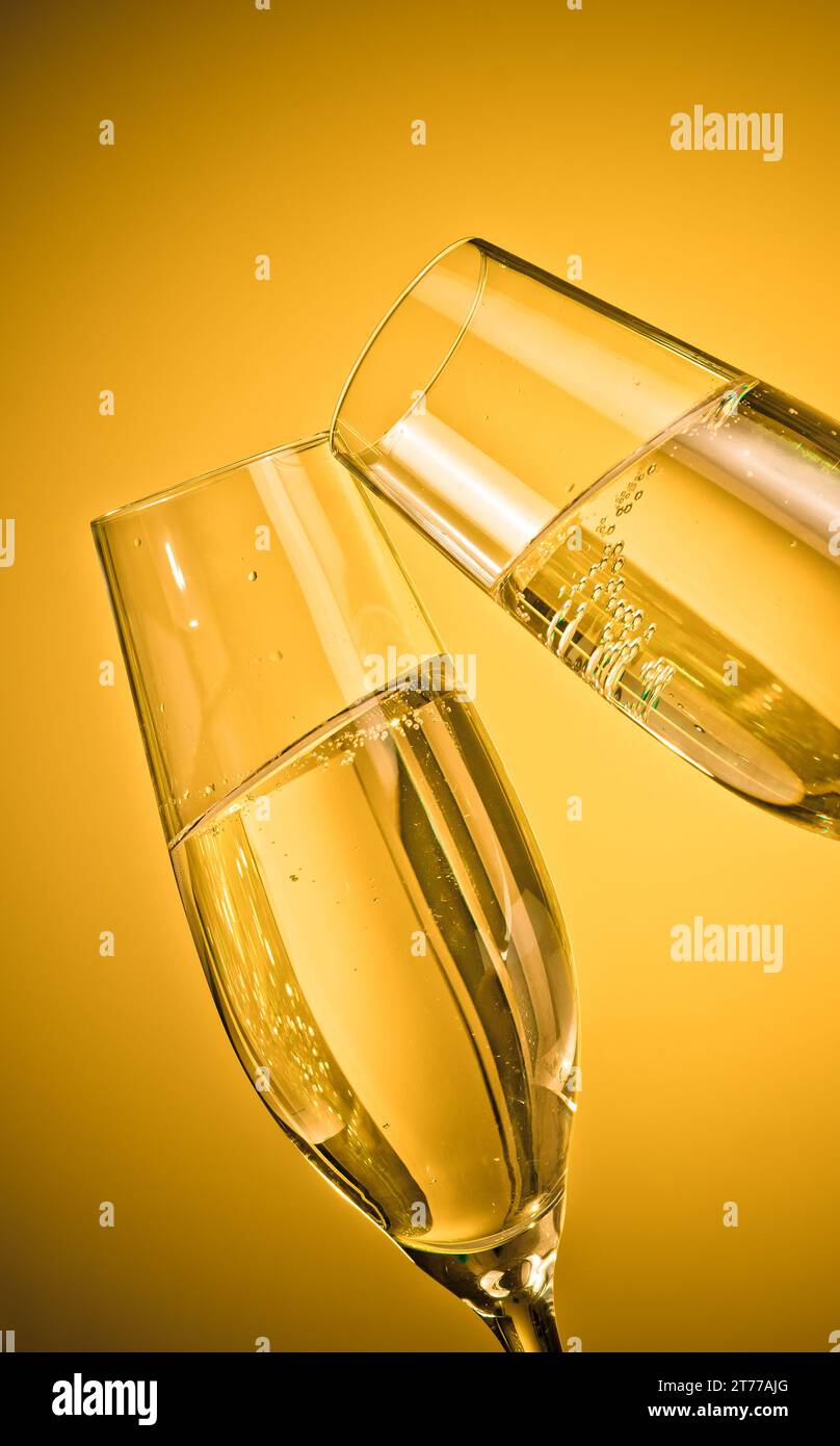 due flute di champagne con bollicine dorate fanno il tifo su sfondo chiaro dorato Foto Stock