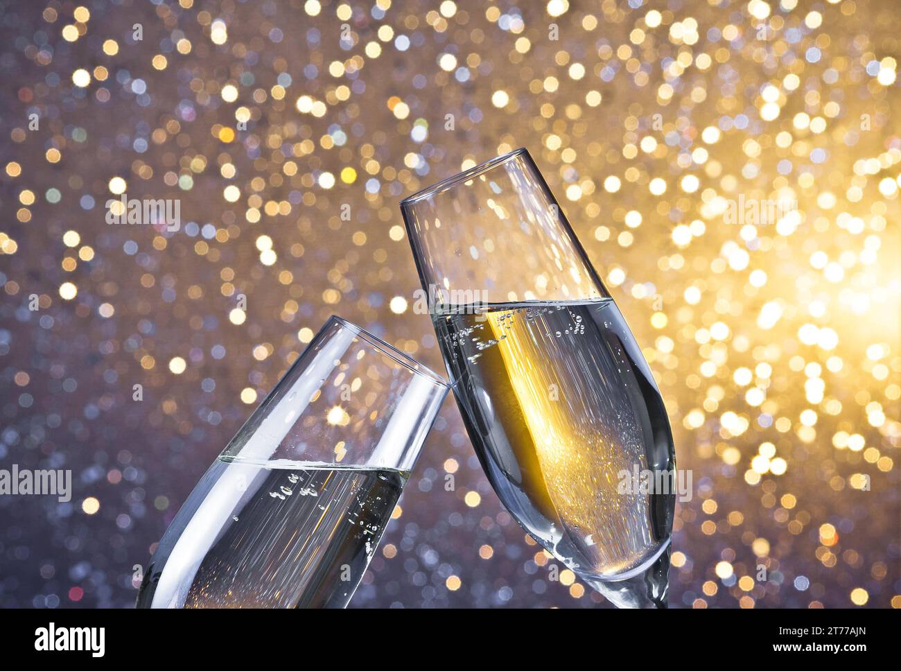 i flauti di champagne con bolle d'oro fanno il tifo su sfondo bokeh chiaro con spazio per il testo Foto Stock