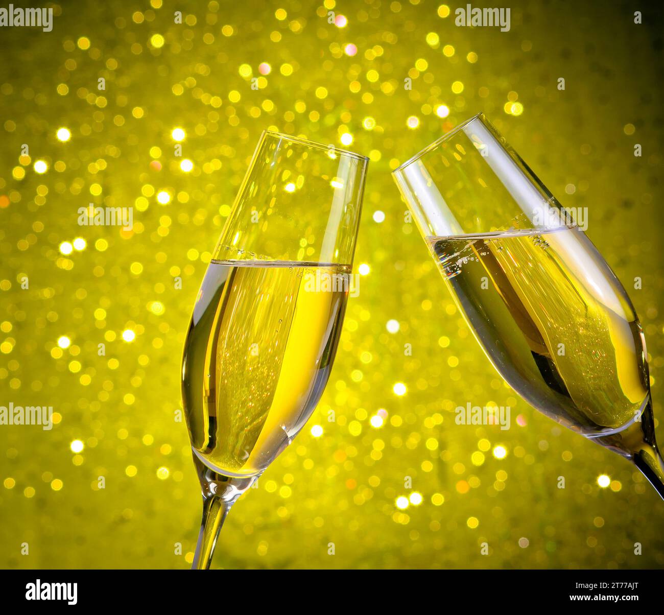 un paio di flauti di champagne con bolle d'oro fanno il tifo su sfondo giallo chiaro bokeh Foto Stock